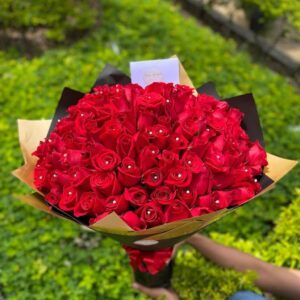 "Impresionante arreglo floral de 100 rosas rojas frescas de tallo largo dispuestas de forma circular y compacta."